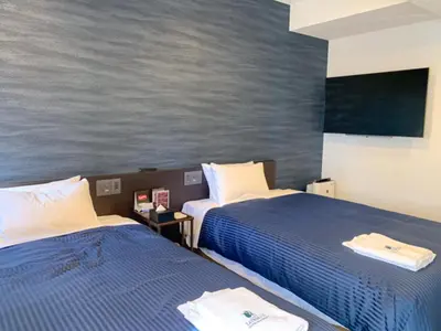 two beds in a hotel room with a painting on the wall at HOTEL LiVEMAX Tokyo Kanda EAST in Tokyo