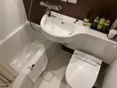 a white bathroom with a toilet and a sink at HOTEL LiVEMAX Tokyo Kanda EAST in Tokyo