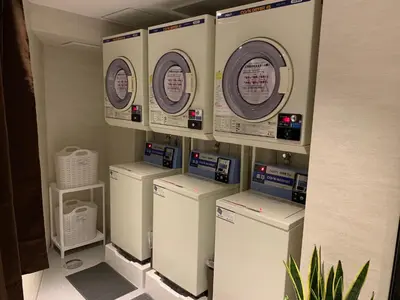 a row of washers and dryers in a laundry room at HOTEL LiVEMAX Tokyo Kanda EAST in Tokyo