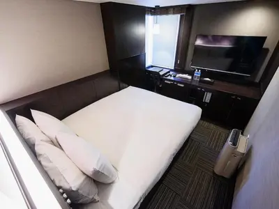 a hotel room with a bed and a television at Meguroholic Hotel in Tokyo