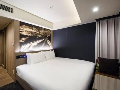a bedroom with a white bed and a painting on the wall at Meguroholic Hotel in Tokyo
