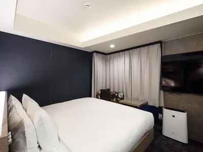 a bedroom with a white bed and a black wall at Meguroholic Hotel in Tokyo