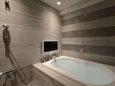 a bathroom with a tub and a tv on the wall at Meguroholic Hotel in Tokyo