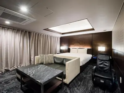 a hotel room with a bed and a couch and a table at Meguroholic Hotel in Tokyo