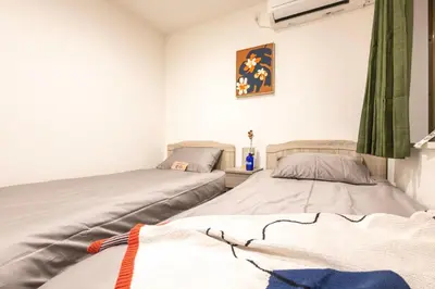 two twin beds in a room with avertisement for at ZAITO Tokyo Chitose Accommodation \u68ee\u4e0b\u99c5\u304b\u3089\u5f92\u6b696\u5206 in Tokyo