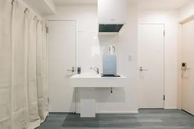 a white bathroom with a sink and a soap dispenser at ZAITO Tokyo Chitose Accommodation \u68ee\u4e0b\u99c5\u304b\u3089\u5f92\u6b696\u5206 in Tokyo