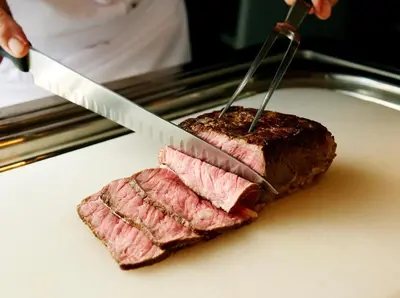 a person cutting a piece of meat with a knife at Villa Fontaine Grand Tokyo Ariake in Tokyo