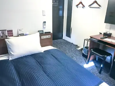 a bedroom with a bed and a desk and a computer at HOTEL LiVEMAX Shinjuku Kabukicho-Meijidori in Tokyo