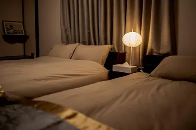 two beds in a hotel room with a lamp and a window at HIRAI UTOPIA HOTEL in Tokyo