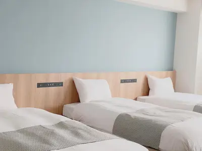 two beds in a room with white sheets and pillows at THE TOURIST HOTEL & Cafe AKIHABARA in Tokyo
