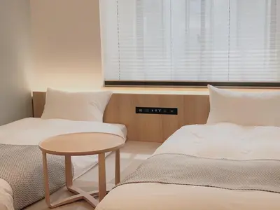 two beds in a room with a table and a window at THE TOURIST HOTEL & Cafe AKIHABARA in Tokyo