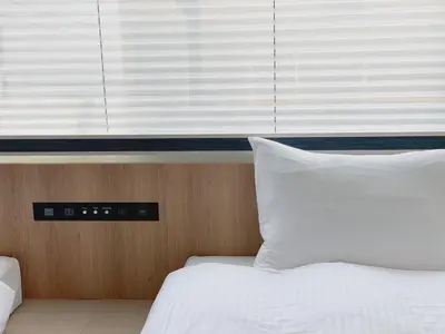 a bedroom with a bed and a window with white pillows at THE TOURIST HOTEL & Cafe AKIHABARA in Tokyo