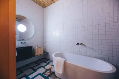 a white bathroom with a tub and a mirror at Hotel K5 in Tokyo
