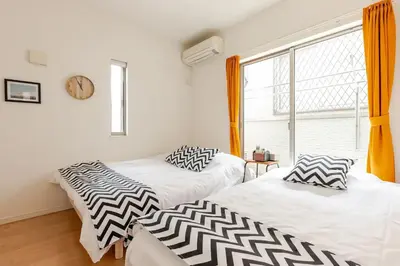 two beds in a room with a clock on the wall at Ishihara House in Tokyo