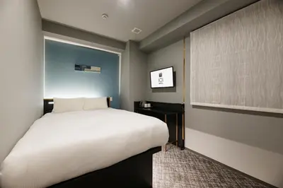 a bedroom with a large white bed and a window at ICI HOTEL Tokyo Hatchobori in Tokyo