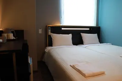a bed with a white blanket on it with a window at ICI HOTEL Tokyo Hatchobori in Tokyo