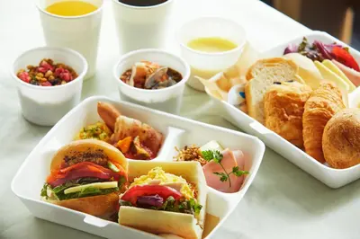 a table topped with three trays of sandwiches and dips at ICI HOTEL Tokyo Hatchobori in Tokyo
