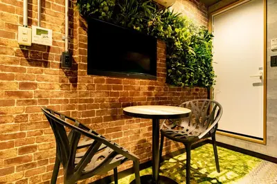 a table and two chairs in front of a brick wall at UNDER RAILWAY HOTEL AKIHABARA in Tokyo