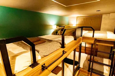 two bunk beds in a room with a green wall at UNDER RAILWAY HOTEL AKIHABARA in Tokyo