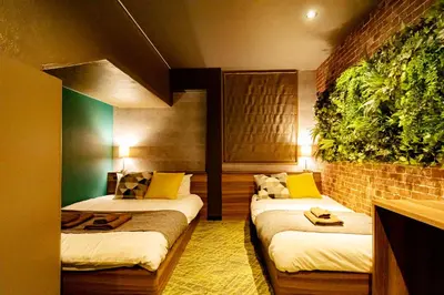 a room with two beds and a plant on the wall at UNDER RAILWAY HOTEL AKIHABARA in Tokyo