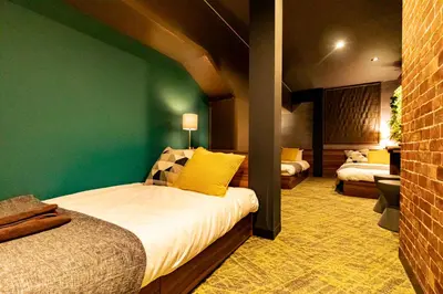 a bedroom with two beds and a green wall at UNDER RAILWAY HOTEL AKIHABARA in Tokyo