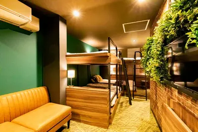a room with bunk beds with a couch and a chair at UNDER RAILWAY HOTEL AKIHABARA in Tokyo