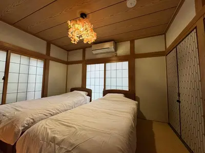 two beds in a room with a chandelier and windows at LEMON TOKYO in Tokyo