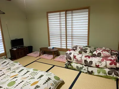 a bedroom with two beds and a table and windows at \u8239\u5800\u30cf\u30a6\u30b9 in Tokyo