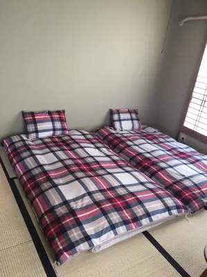 a bed with a plaid blanket and two pillows at \u8239\u5800\u30cf\u30a6\u30b9 in Tokyo