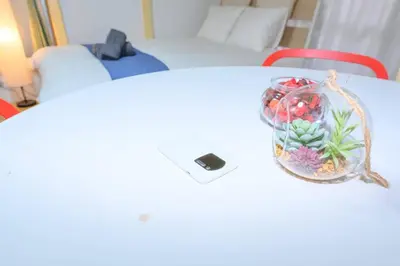 a table with a glass jar of flowers and a cell phone at Cozy house \u845b\u98fe in Tokyo