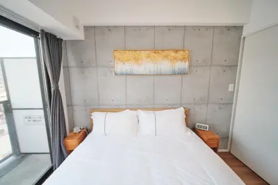 a bedroom with a white bed and a wall at Yoshitsuki kaku - Yoshitsuki Apart Hotel in Tokyo