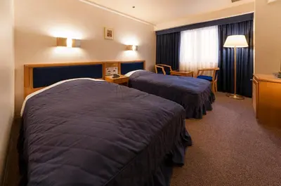 a hotel room with two beds and a table at Hotel Siena in Tokyo