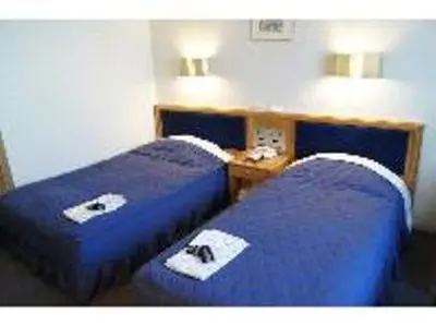 two beds in a hotel room with blue sheets at Hotel Siena in Tokyo