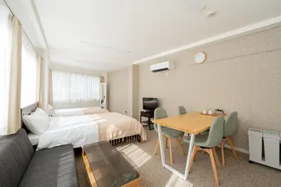 a hotel room with a bed and a table at \u65b0\u5bbf\u307e\u30675\u5206 \u6771\u4e2d\u91ce\u99c5\u5f92\u6b692\u5206 \u685c\u306e\u540d\u6240\u4e07\u4e80\u6a4b\u8fd1\u304f \u6700\u59274\u4eba \u6d17\u6fef\u6a5f \u30c0\u30a4\u30cb\u30f3\u30b0 ILIMA Higashi Nakano in Tokyo