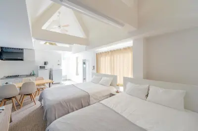 a white bedroom with two beds and a table at \u65b0\u5bbf\u307e\u30675\u5206 \u6771\u4e2d\u91ce\u99c5\u5f92\u6b692\u5206 \u685c\u306e\u540d\u6240\u4e07\u4e80\u6a4b\u8fd1\u304f \u6700\u59274\u4eba \u6d17\u6fef\u6a5f \u30c0\u30a4\u30cb\u30f3\u30b0 ILIMA Higashi Nakano in Tokyo