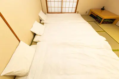 two beds in a room with white sheets at STATION SIDE113 in Tokyo