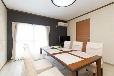 a dining room with a wooden table and white chairs at STATION SIDE113 in Tokyo