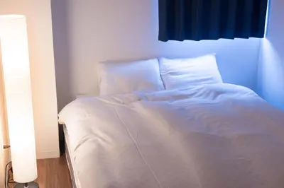a bed with white sheets and pillows in a room at TORA HOTEL Tokyo Skytree \u5bc5\u30db\u30c6\u30eb \u30b9\u30ab\u30a4\u30c4\u30ea\u30fcE in Tokyo