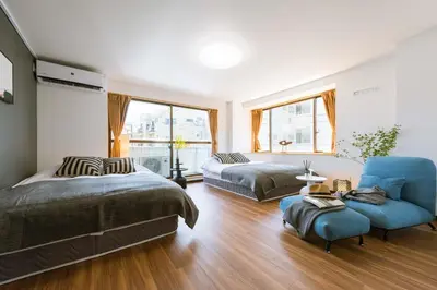 a bedroom with two beds and a blue chair at TORA HOTEL Tokyo-Rikugienn \u5bc5\u30db\u30c6\u30eb \u516d\u7fa9\u5712 C in Tokyo