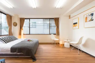 a bedroom with a bed and two chairs and a window at TORA HOTEL Tokyo-Rikugienn \u5bc5\u30db\u30c6\u30eb \u516d\u7fa9\u5712 B in Tokyo