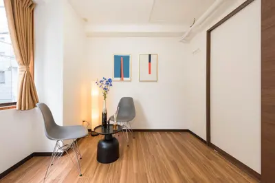a room with two chairs and a vase with flowers at TORA HOTEL Tokyo-Rikugienn \u5bc5\u30db\u30c6\u30eb \u516d\u7fa9\u5712 B in Tokyo