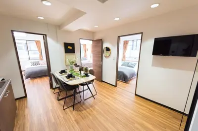 a living room with a table with chairs and a television at TORA HOTEL Tokyo-Rikugienn \u5bc5\u30db\u30c6\u30eb \u516d\u7fa9\u5712 B in Tokyo