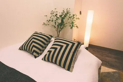 a bed with two pillows and a vase on it at TORA HOTEL Tokyo-Rikugienn \u5bc5\u30db\u30c6\u30eb \u516d\u7fa9\u5712 A in Tokyo