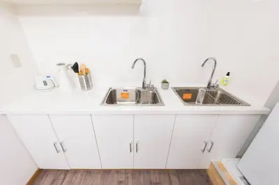 a kitchen with white cabinets and two sinks at TORA HOTEL Tokyo-Rikugienn \u5bc5\u30db\u30c6\u30eb \u516d\u7fa9\u5712 A in Tokyo