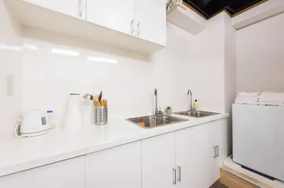 a white kitchen with white cabinets and a sink at TORA HOTEL Tokyo-Rikugienn \u5bc5\u30db\u30c6\u30eb \u516d\u7fa9\u5712 A in Tokyo