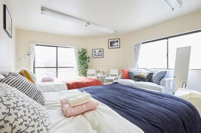 a bedroom with two beds and a couch at TORA HOTEL Tokyo-kitaueno \u5bc5\u30db\u30c6\u30eb\u5317\u4e0a\u91ce in Tokyo