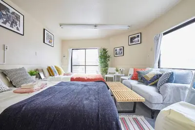 a living room with two beds and a couch at TORA HOTEL Tokyo-kitaueno \u5bc5\u30db\u30c6\u30eb\u5317\u4e0a\u91ce in Tokyo
