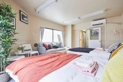 a bedroom with two beds and a couch at TORA HOTEL Tokyo-kitaueno \u5bc5\u30db\u30c6\u30eb\u5317\u4e0a\u91ce in Tokyo