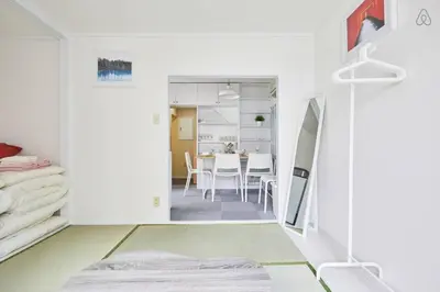 a bedroom with white walls and a dining room with a table at TORA HOTEL Tokyo-kitaueno \u5bc5\u30db\u30c6\u30eb\u5317\u4e0a\u91ce in Tokyo