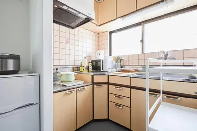 a kitchen with wooden cabinets and a white refrigerator at TORA HOTEL Tokyo-kitaueno \u5bc5\u30db\u30c6\u30eb\u5317\u4e0a\u91ce in Tokyo